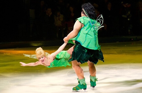 Bre dressed as a green fairy mid air as another skater spins her around
